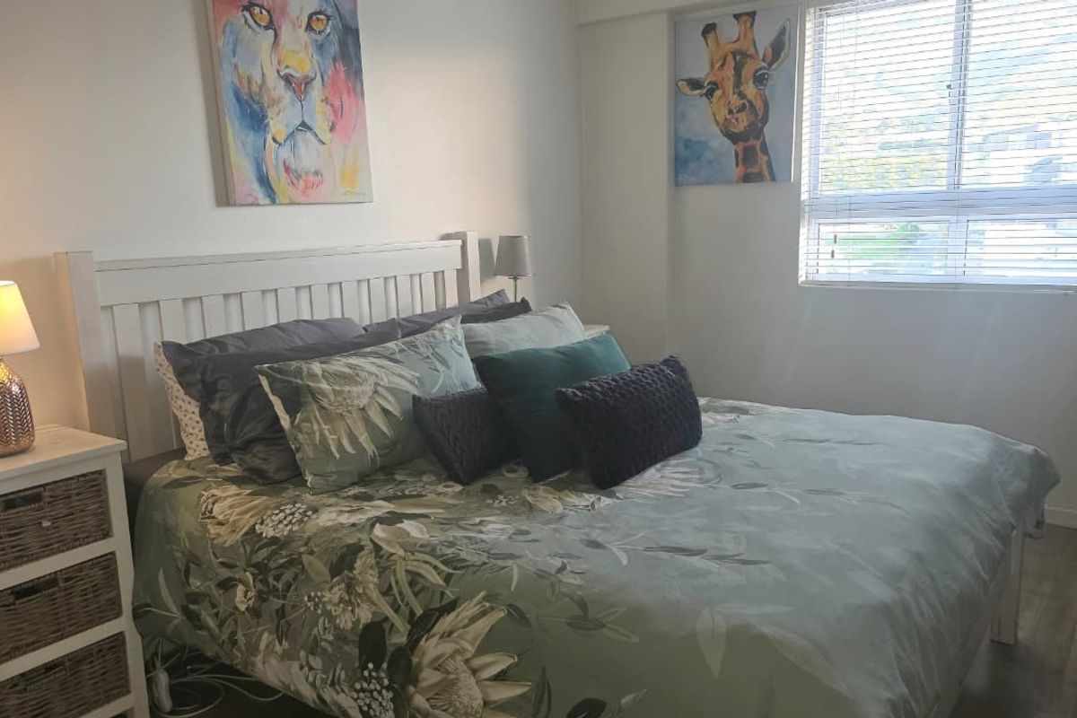 A well-lit bedroom featuring neutral walls, laminate flooring, and venetian blinds, providing a comfortable and functional living space.