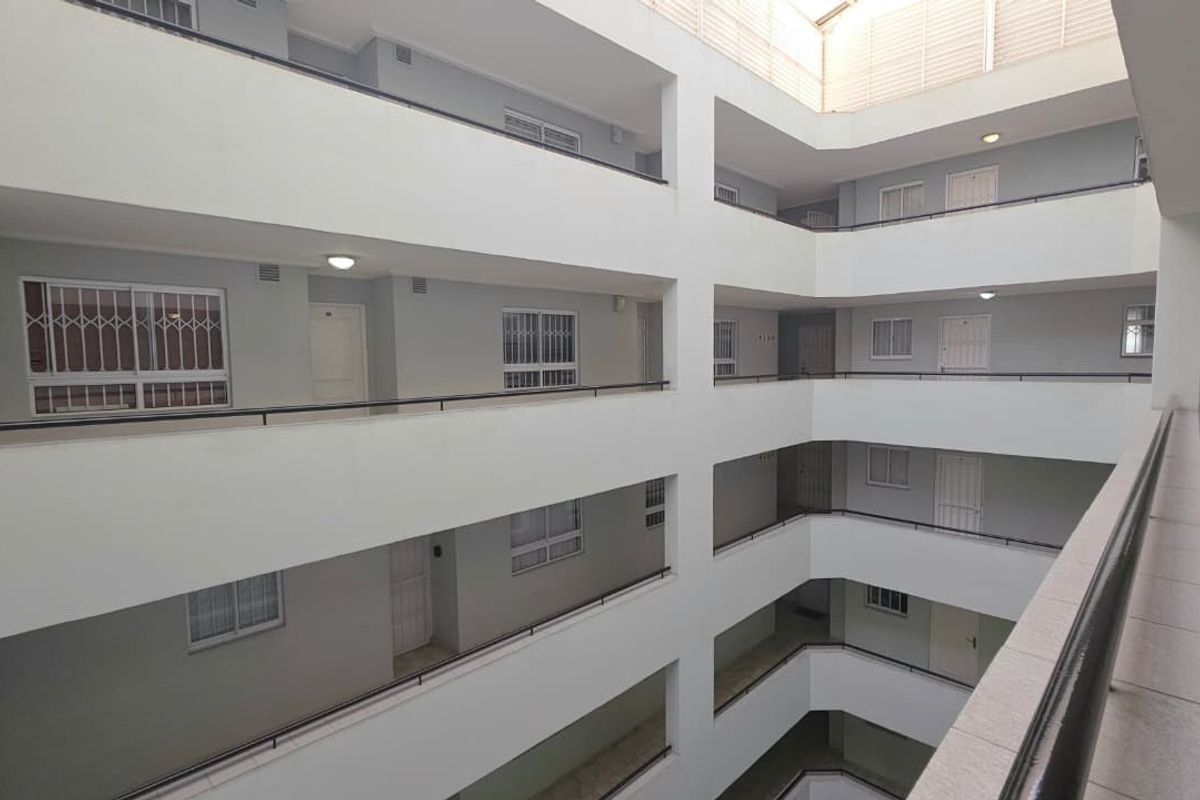 A view of the apartment building's central atrium, featuring multi-level walkways with security gates and balustrades.