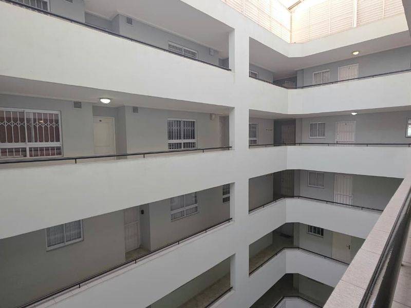 A view of the apartment building's central atrium, featuring multi-level walkways with security gates and balustrades.
