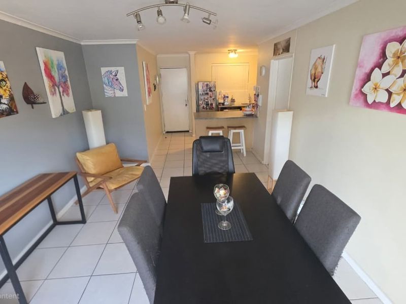 Open plan living and dining area featuring tiled flooring, track lighting, and a breakfast bar connecting to the kitchen space.