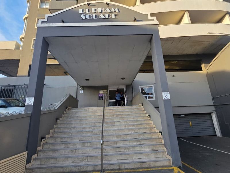 Front entrance of Durham Square apartment building featuring a concrete staircase, covered portico, and secure access point.