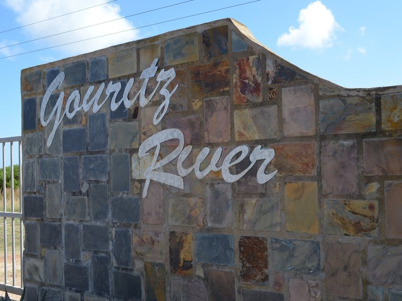 A stone-clad entrance wall featuring the Gouritz River signage and a metal gate, marking the boundary of the residential property.