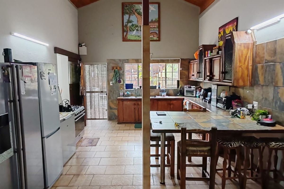 Spacious kitchen featuring vaulted ceilings, built-in wooden cabinetry, tiled backsplash, and a central breakfast bar area.