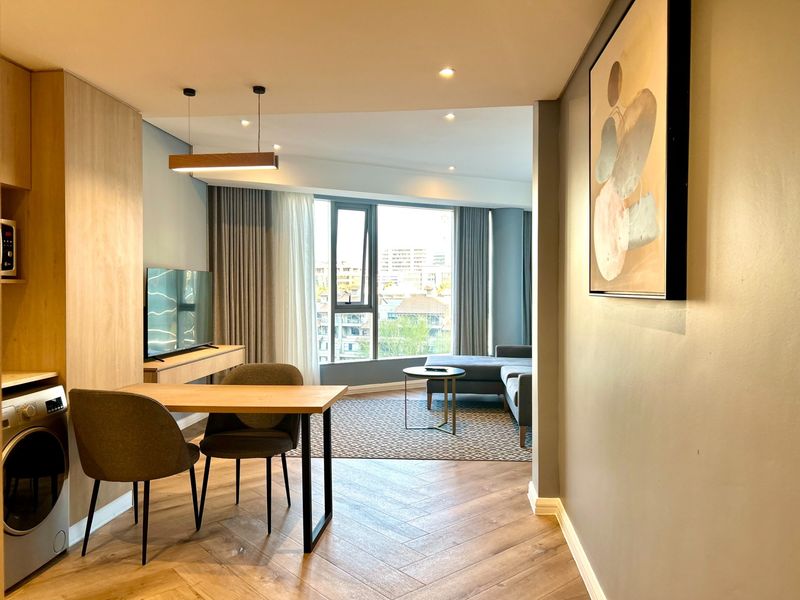 Modern open-plan living area featuring high-quality herringbone timber flooring, recessed lighting, and integrated cabinetry with a built-in laundry appliance.