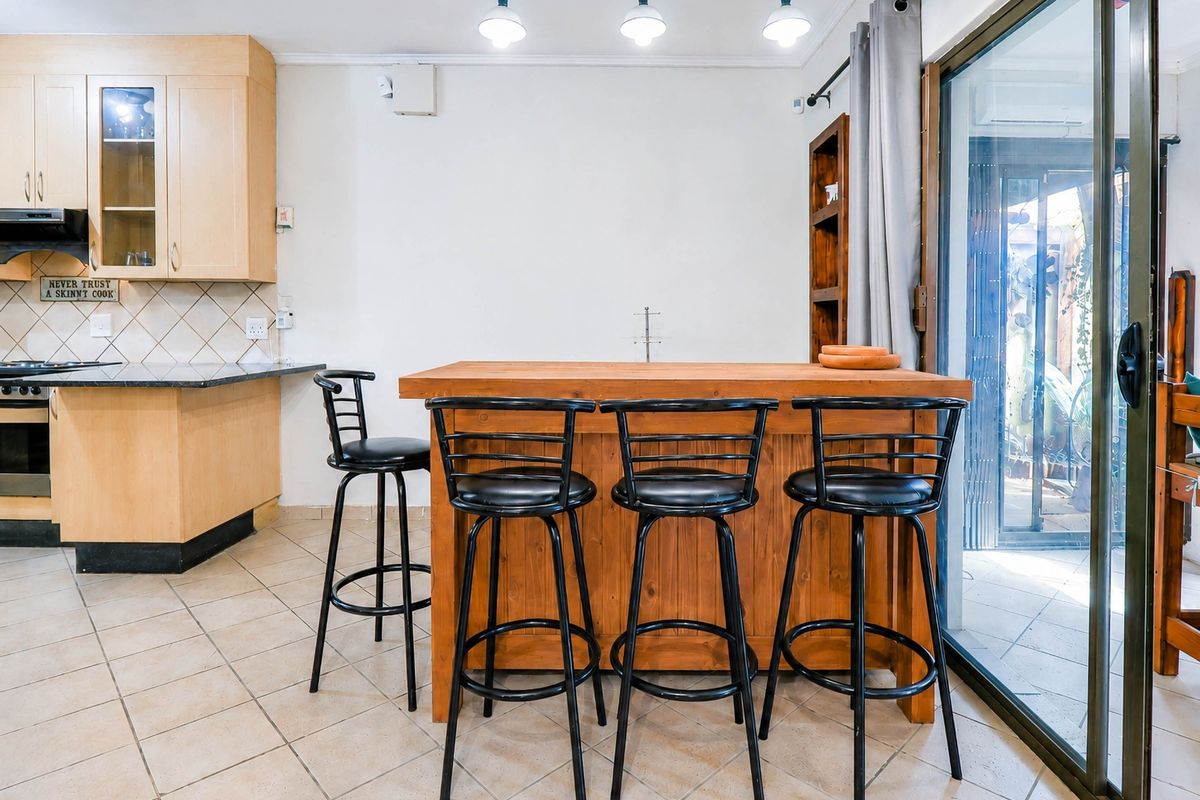Kitchen featuring light wood cabinetry, granite countertops, built-in appliances, and tiled flooring, with direct access to an outdoor area via sliding glass doors.