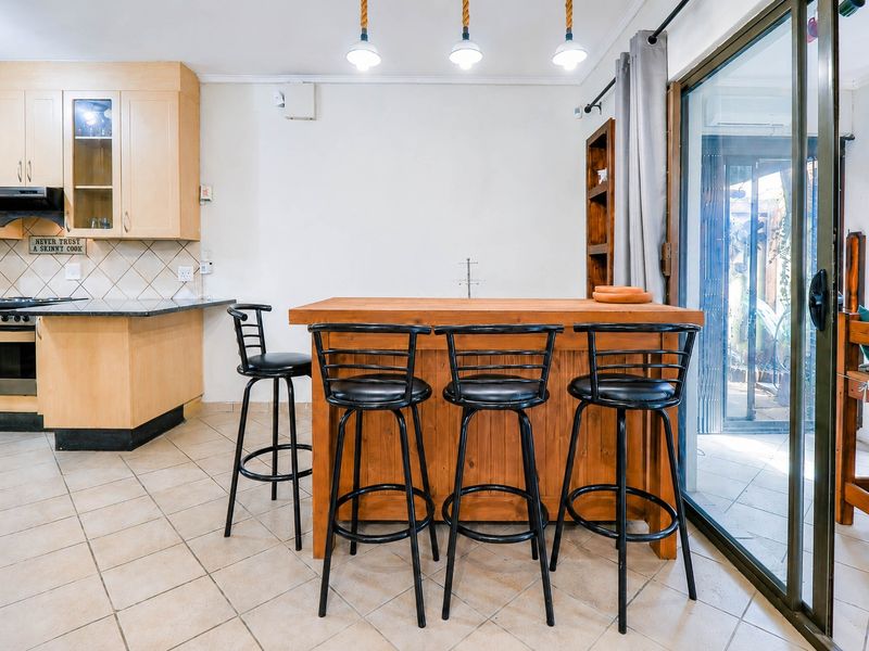 Kitchen featuring light wood cabinetry, granite countertops, built-in appliances, and tiled flooring, with direct access to an outdoor area via sliding glass doors.