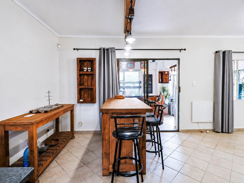 Open plan living area featuring tiled flooring, an exposed ceiling beam, and a sliding glass door providing access to the patio.