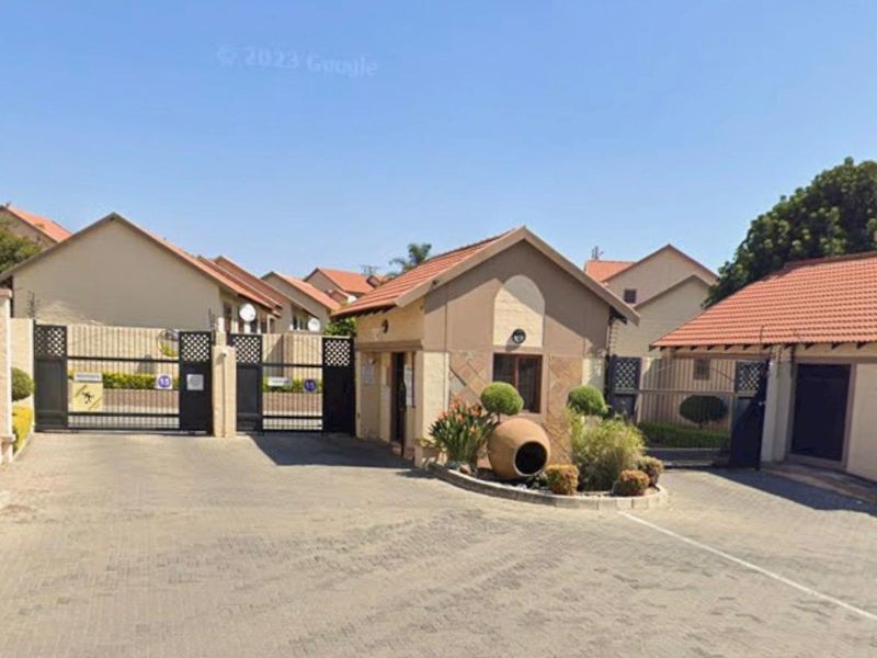 The entrance to the residential complex features a paved driveway, secure gated access, and a dedicated guard house.
