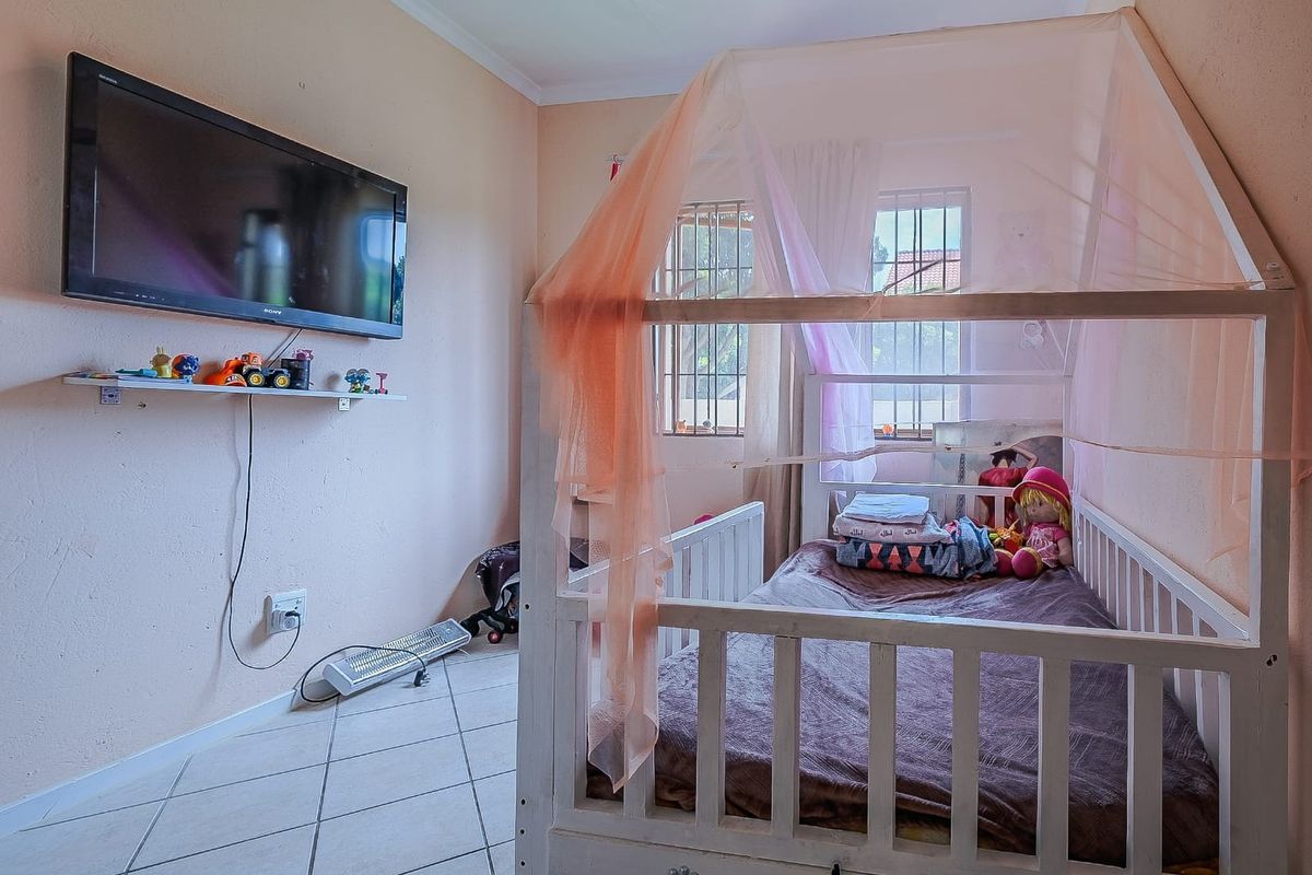 A bedroom featuring tiled flooring and windows fitted with security bars, providing a functional space with potential for cosmetic updates.