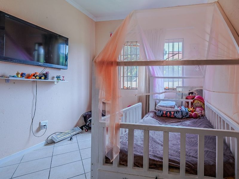 A bedroom featuring tiled flooring and windows fitted with security bars, providing a functional space with potential for cosmetic updates.