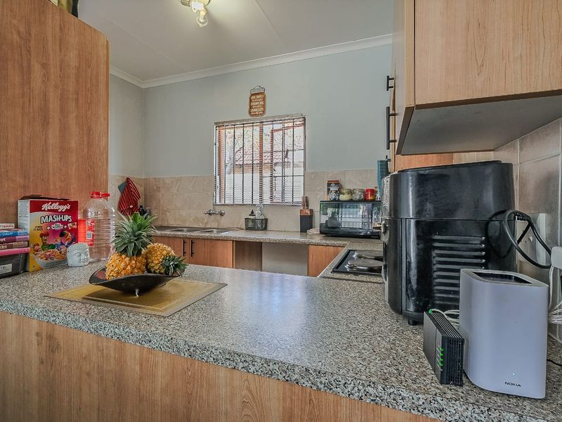 A functional kitchen featuring laminate cabinetry, granite countertops, a tiled backsplash, and a built-in hob, offering a practical layout for daily meal preparation.