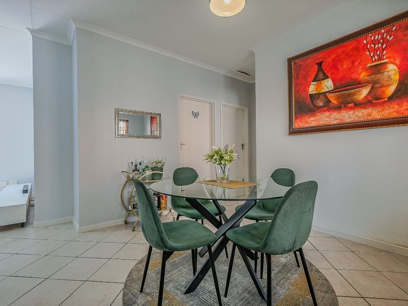 A bright dining area featuring neutral walls, tiled flooring, and classic cove cornicing, providing a clean and functional space for meals.