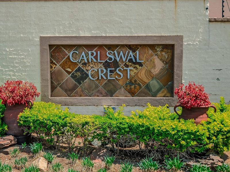 A decorative stone-clad signage wall for Carlswal Crest, featuring integrated lettering and surrounding landscaped garden beds.