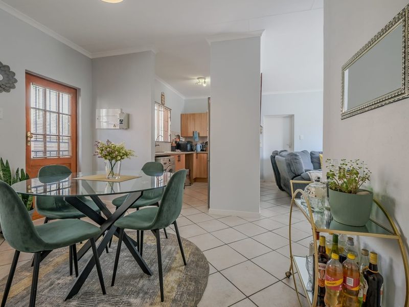 Open-plan dining area featuring tiled flooring and direct access to the kitchen and living space, with a classic timber-framed glass door.