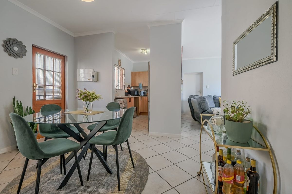 Open-plan dining area featuring tiled flooring and direct access to the kitchen and living space, with a classic timber-framed glass door.