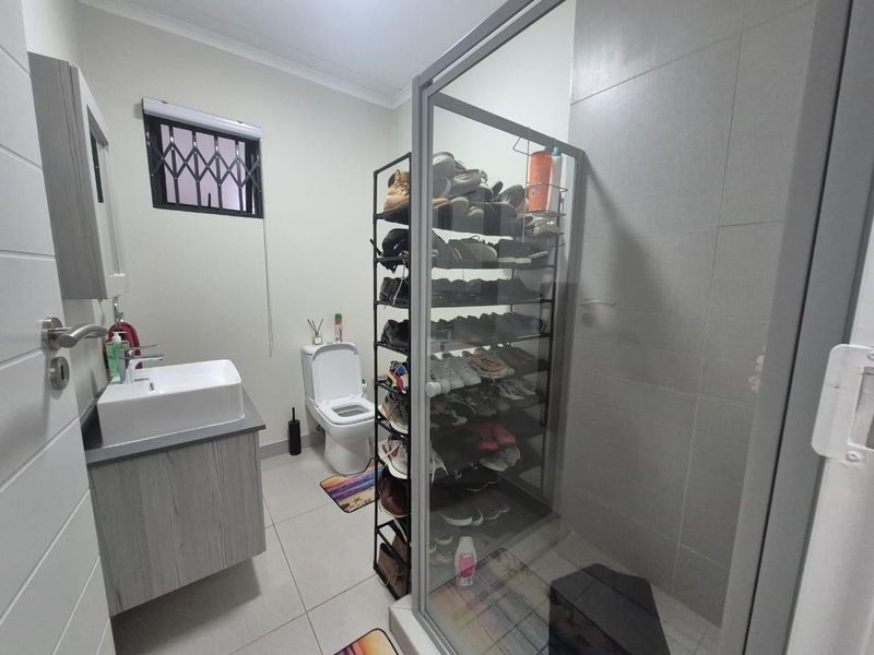 Modern bathroom featuring a vanity with basin, toilet, and a glass-enclosed shower with tiled finishes.