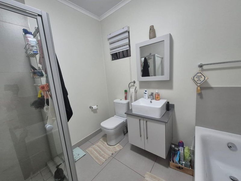 A functional bathroom featuring a shower enclosure, a separate bathtub, a modern vessel sink with a vanity cabinet, and neutral tiled flooring.