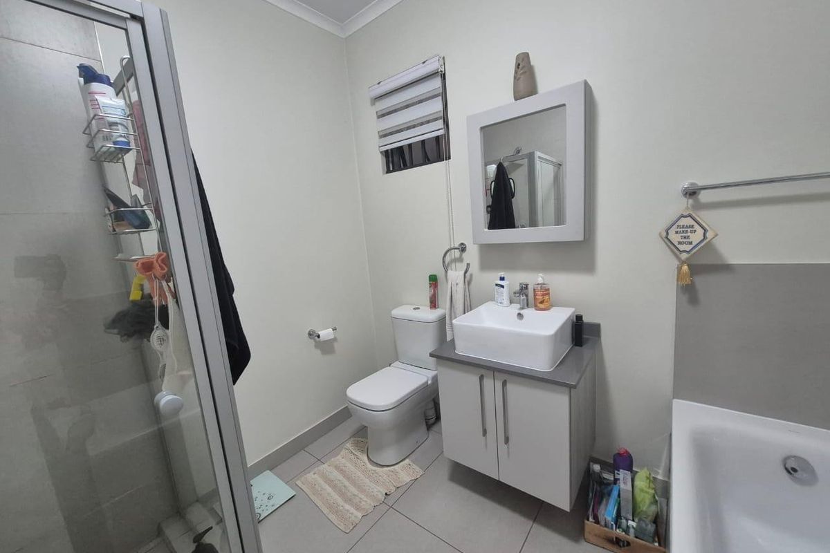 A functional bathroom featuring a shower enclosure, a separate bathtub, a modern vessel sink with a vanity cabinet, and neutral tiled flooring.