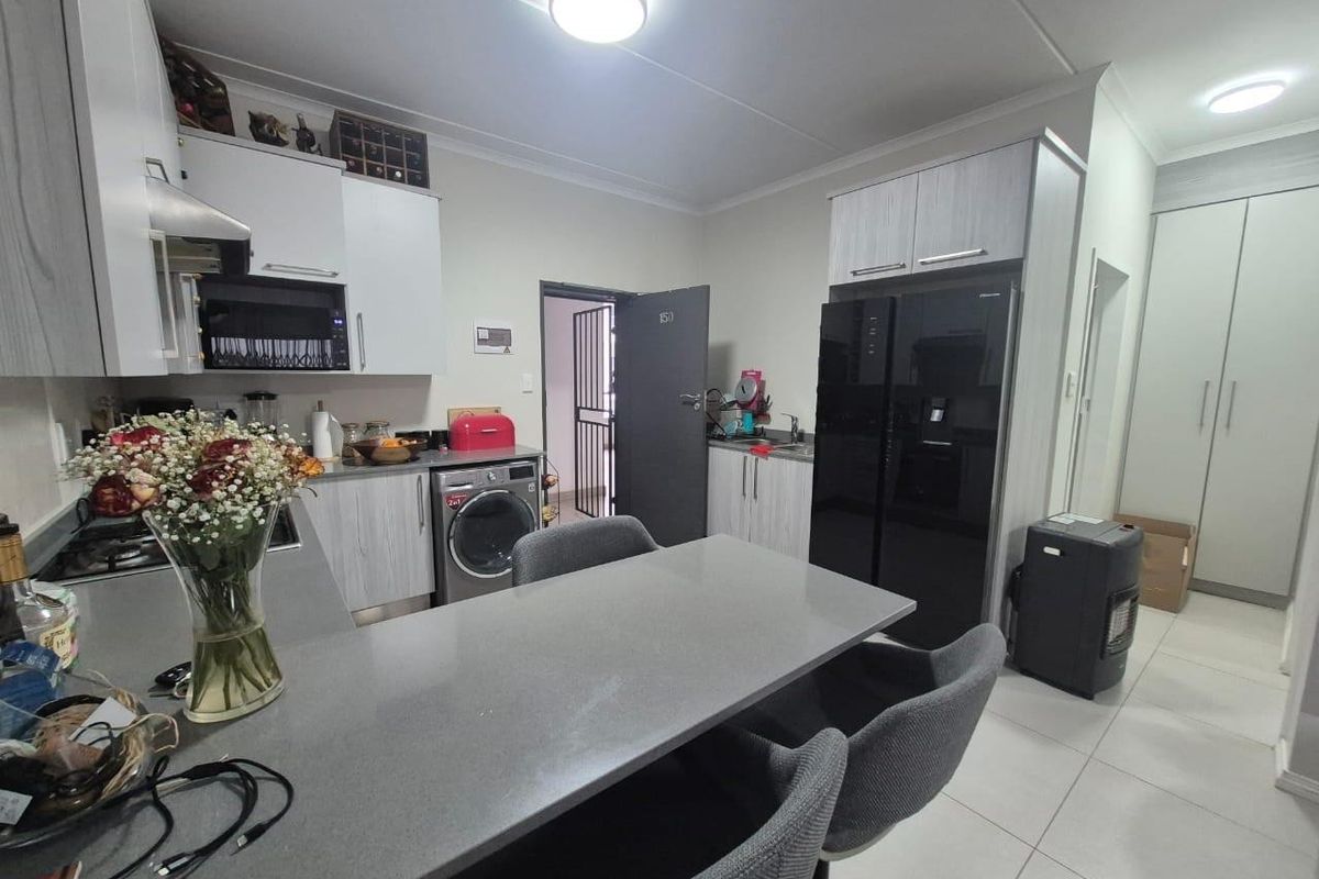 Modern kitchen featuring sleek built-in cabinetry, stone countertops, integrated appliances, and tiled flooring, offering a functional and contemporary cooking and dining space.