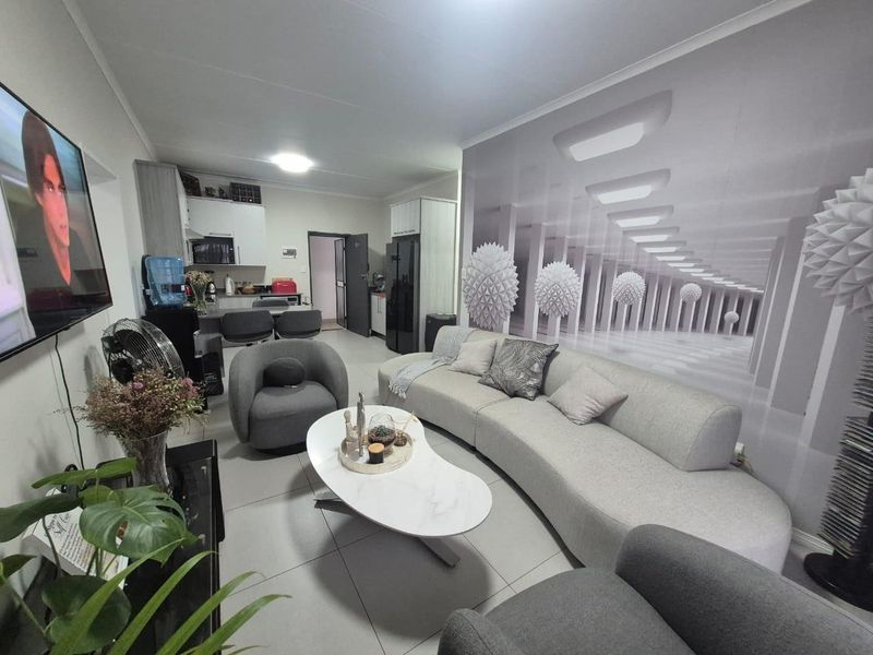 An open-plan living and kitchen area featuring tiled flooring, modern cabinetry, and a spacious layout suitable for comfortable apartment living.