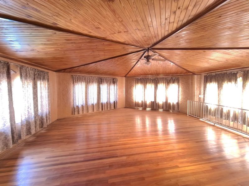 Spacious living area featuring a distinctive timber-clad vaulted ceiling, polished hardwood flooring, and a metal balustrade overlooking the lower level.