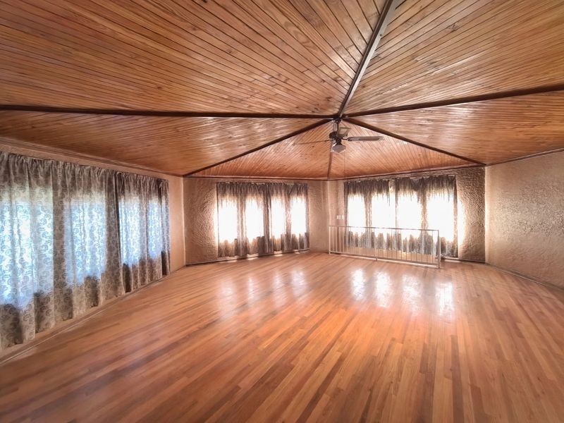 Spacious living area featuring a distinctive vaulted timber ceiling, hardwood flooring, and textured walls, offering a bright and open layout.