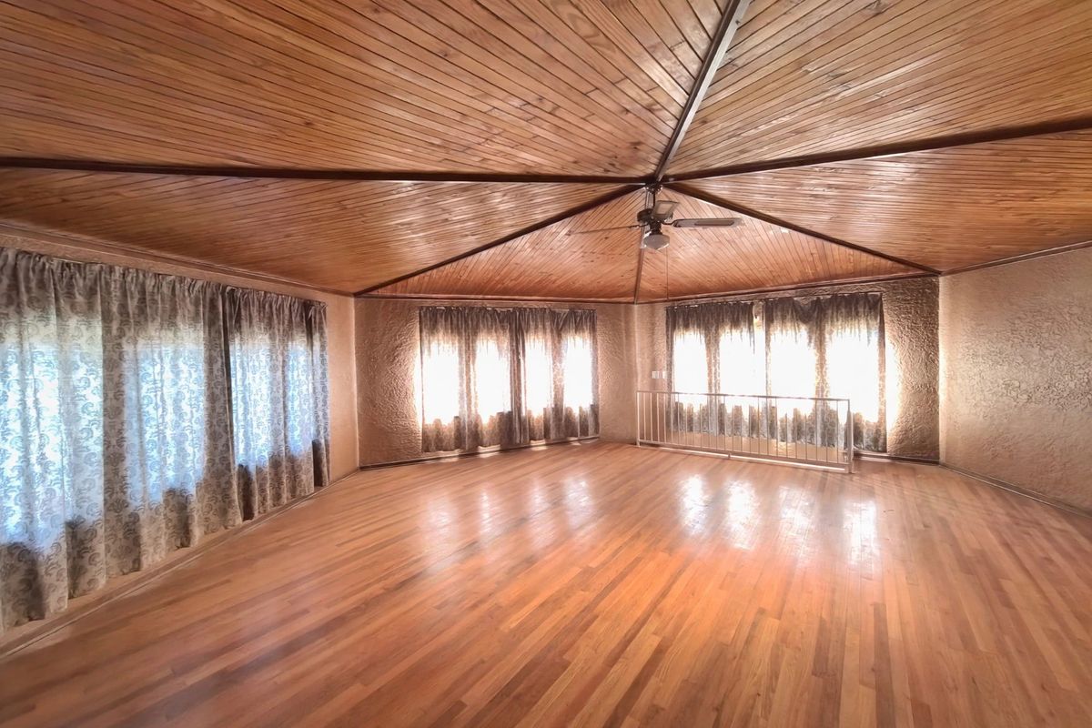 Spacious living area featuring a distinctive vaulted timber ceiling, hardwood flooring, and textured walls, offering a bright and open layout.