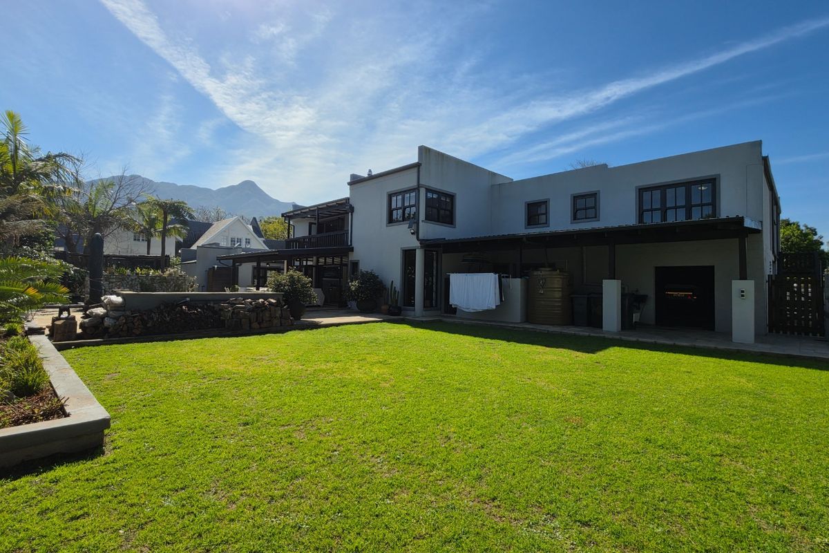 Spacious rear garden featuring a well-maintained lawn, covered patio area, and mountain views, providing an ideal space for outdoor living and relaxation.