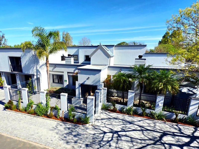 A modern multi-level residential property featuring a paved driveway, secure metal fencing, and well-maintained exterior facade with integrated lighting.