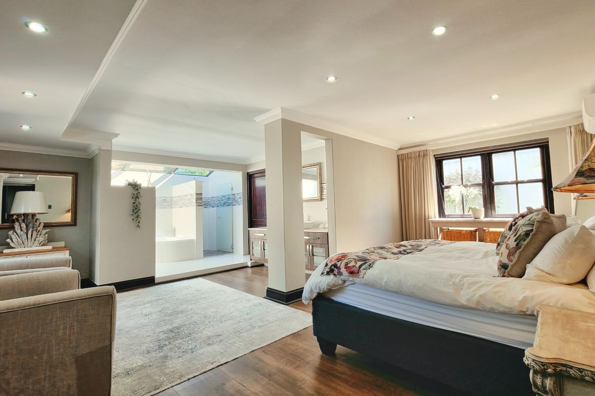 Spacious master bedroom featuring an open-plan en-suite bathroom with a skylight, recessed lighting, and modern laminate flooring.
