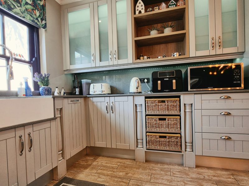 A well-appointed kitchen featuring shaker-style cabinetry, a farmhouse sink, stone countertops, and integrated storage solutions with elegant under-cabinet lighting.
