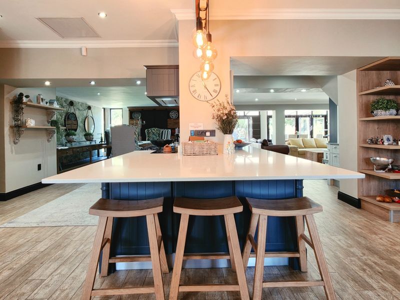 Spacious open-plan kitchen featuring a large central island with quartz countertops, custom cabinetry, and integrated lighting, flowing into the adjacent living and dining areas.