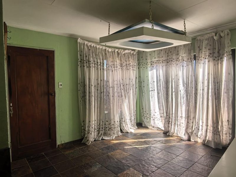 An empty living area featuring slate tile flooring, a unique suspended ceiling light fixture, and direct access through a timber door.
