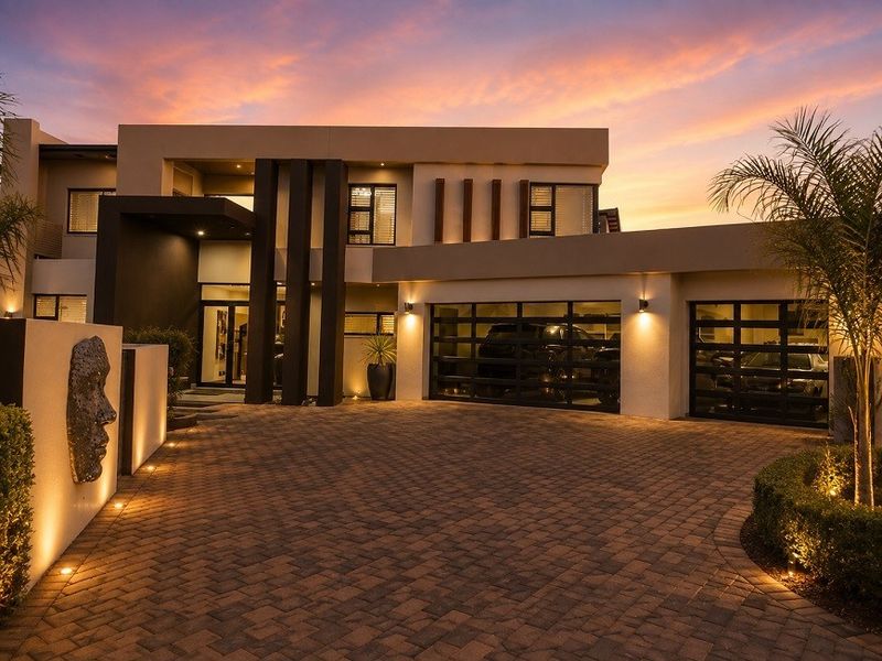 Stunning modern architectural home exterior at dusk, featuring a paved driveway, double garage with glass panel doors, and sophisticated exterior lighting.