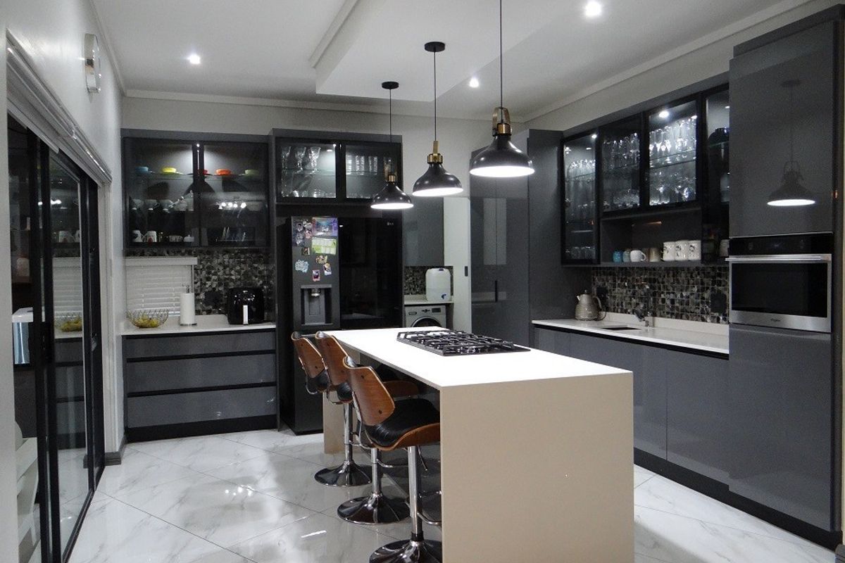 Modern kitchen featuring a central island with a gas cooktop, sleek dark cabinetry, glass-front display units, and high-end finishes throughout.