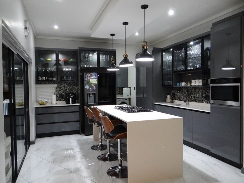 Modern kitchen featuring a central island with a gas cooktop, sleek dark cabinetry, glass-front display units, and high-end finishes throughout.