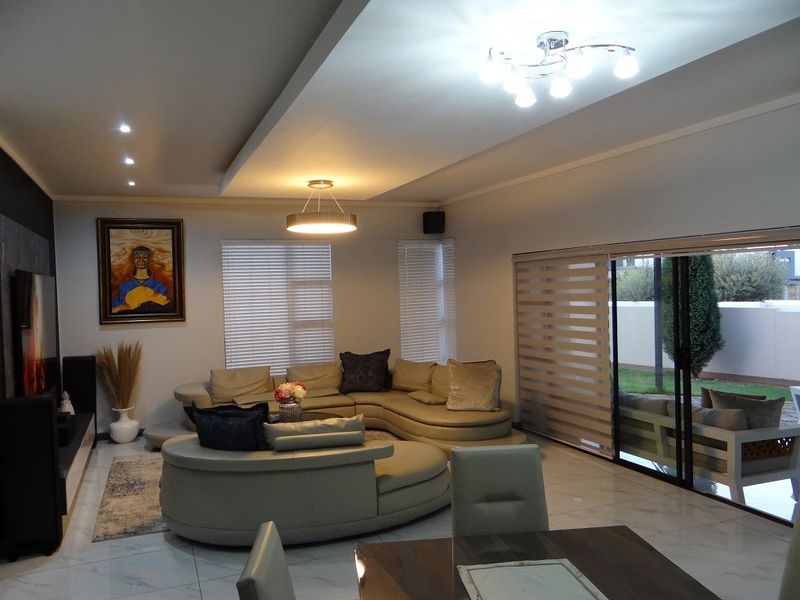 Spacious open-plan living area featuring modern tiled floors, recessed ceiling lighting, and large sliding glass doors providing seamless access to the outdoor patio.