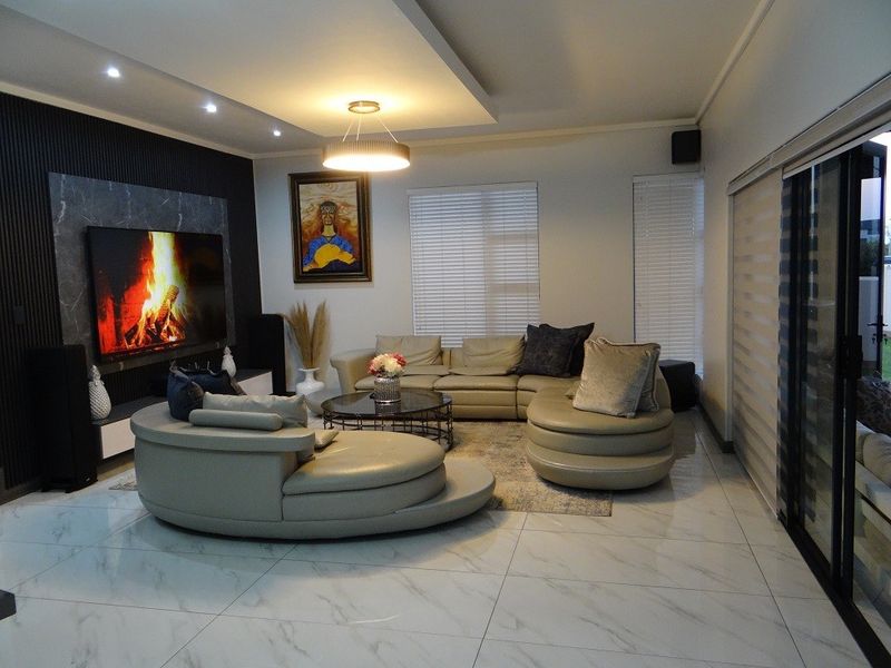 Modern living room featuring marble-look floor tiles, recessed ceiling lighting, feature wall paneling, and large sliding glass doors leading to the exterior.