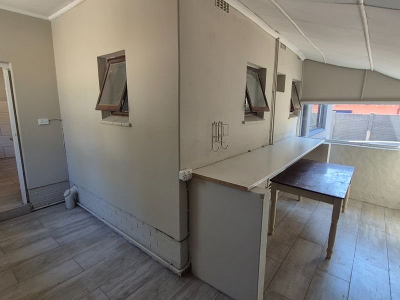 A functional scullery or utility area featuring tiled flooring, built-in counter space, and top-hung windows, providing a practical workspace adjacent to the main kitchen.