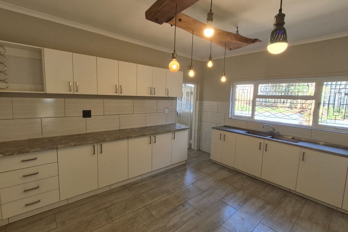 A clean, modern kitchen featuring white cabinetry, granite countertops, tiled backsplash, and unique pendant lighting, offering a bright and functional workspace.