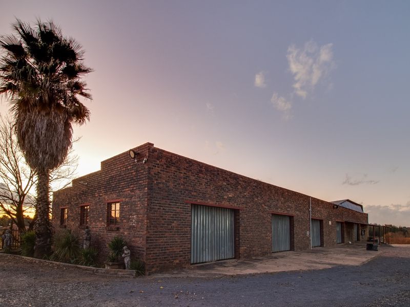 Industrial property featuring a face brick facade with multiple metal roller shutter doors and exterior security lighting.