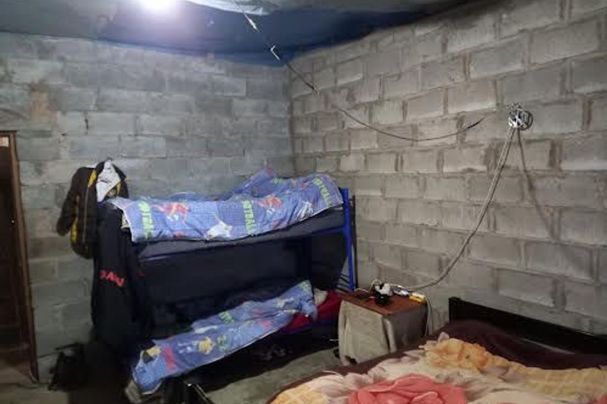 A bedroom featuring unfinished concrete block walls and exposed ceiling structure, requiring significant interior finishing and electrical work.
