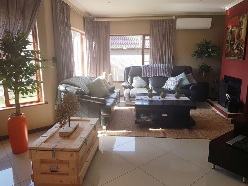 A comfortable living room featuring large windows, tiled flooring, a fireplace, and a wall-mounted air conditioning unit.