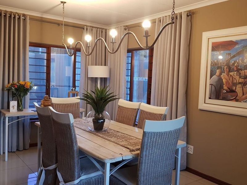 A well-lit dining room featuring tiled floors, large sliding glass doors with security bars, and a modern decorative pendant light fixture.