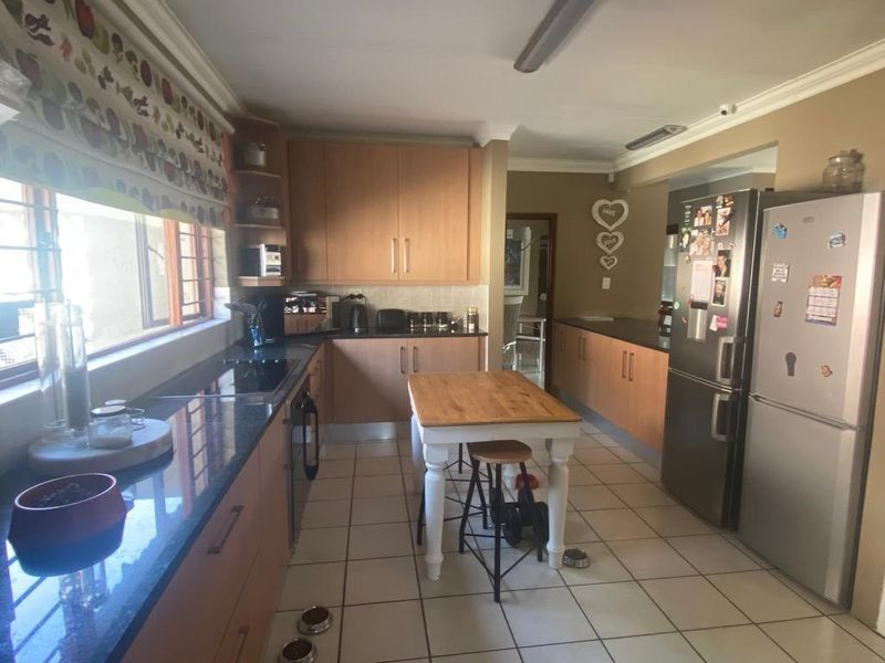 A functional kitchen featuring light wood cabinetry, dark granite countertops, ceramic tile flooring, and integrated cooking appliances.