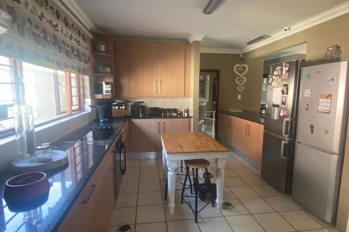 A functional kitchen featuring light wood cabinetry, dark granite countertops, ceramic tile flooring, and integrated cooking appliances.