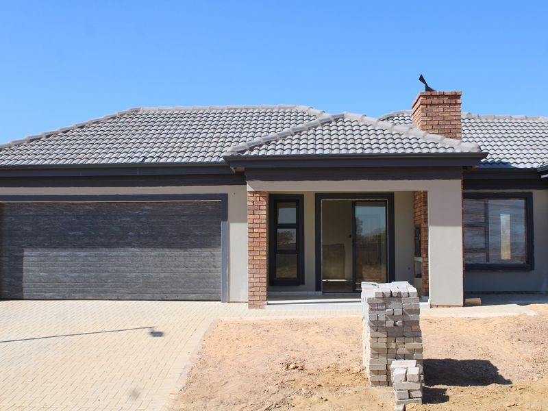 Front elevation of a modern single-story house featuring a tiled roof, brick accents, a double garage, and a paved driveway.