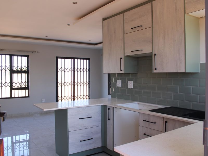 Modern kitchen featuring light wood-grain cabinetry, stone countertops, and a stylish subway tile backsplash, ready for final appliance installation.