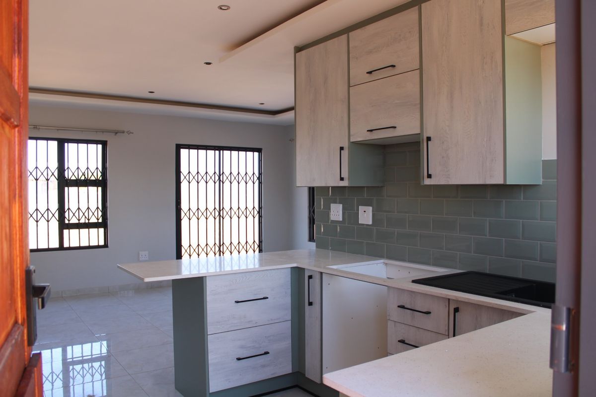Modern kitchen featuring light wood-grain cabinetry, stone countertops, and a stylish subway tile backsplash, ready for final appliance installation.