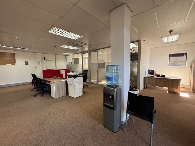 Open plan office space featuring suspended ceilings, recessed lighting, and glass partition walls, providing a functional layout for a professional work environment.